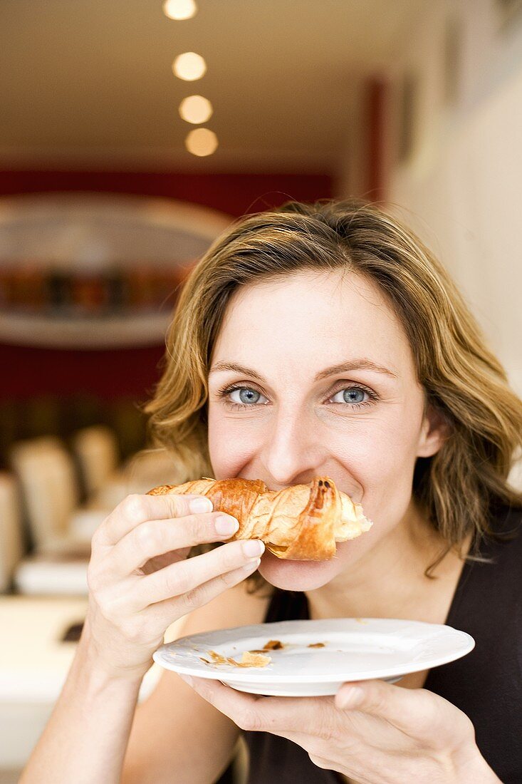 Woman biting into a croissant