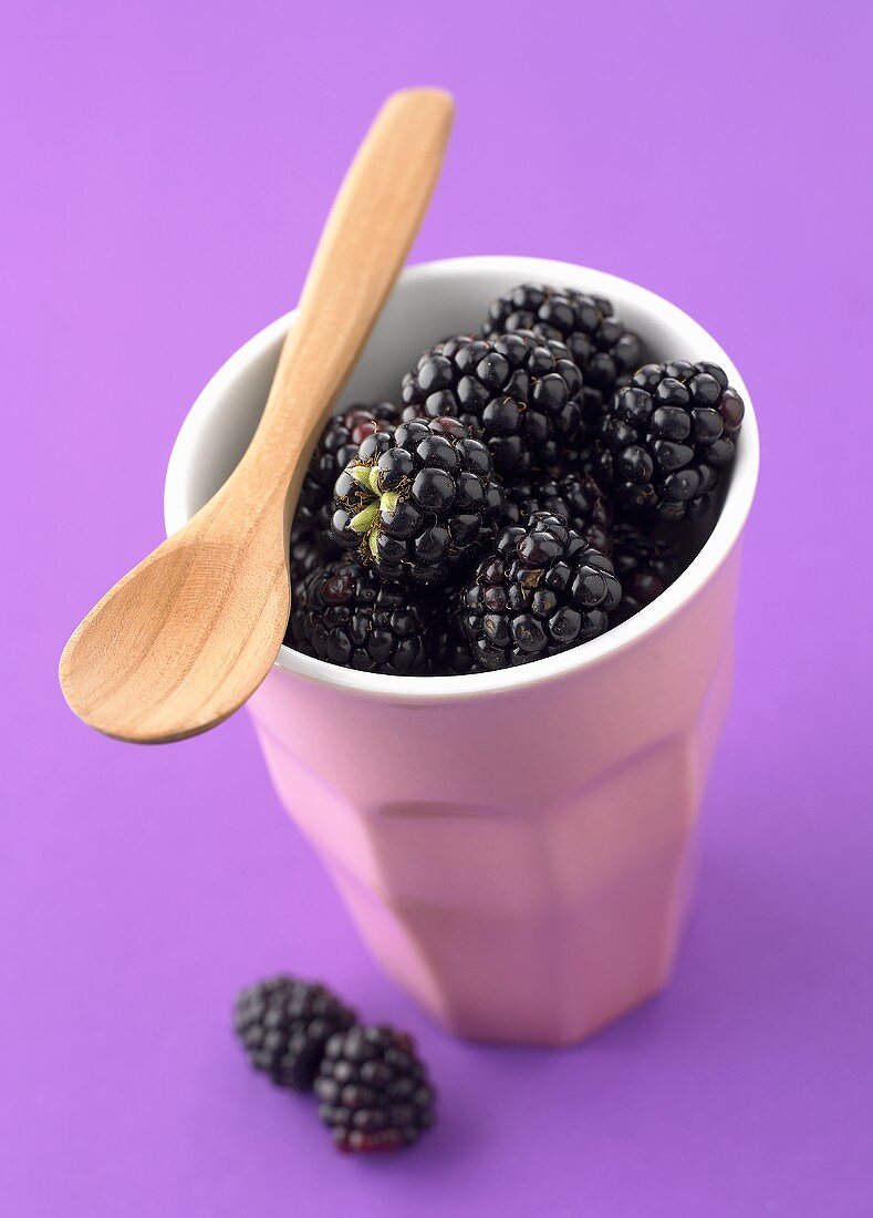 Fresh blackberries in a beaker with wooden spoon