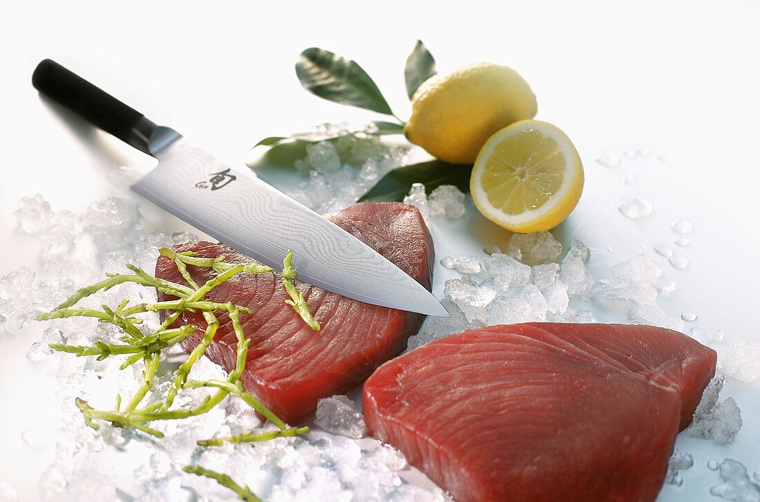 Two tuna steaks on ice with knife