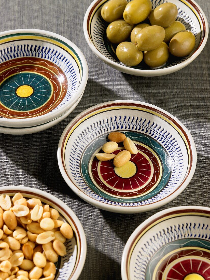 Peanuts and green olives in small bowls