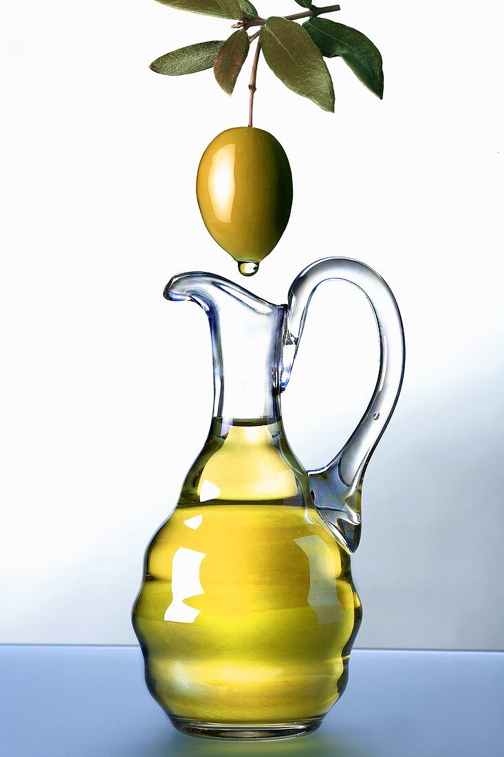 Olive oil dripping from an olive into a carafe