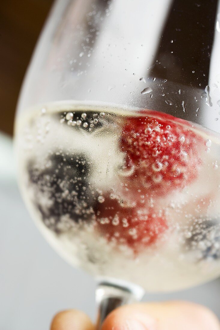 A glass of champagne with berry ice cubes