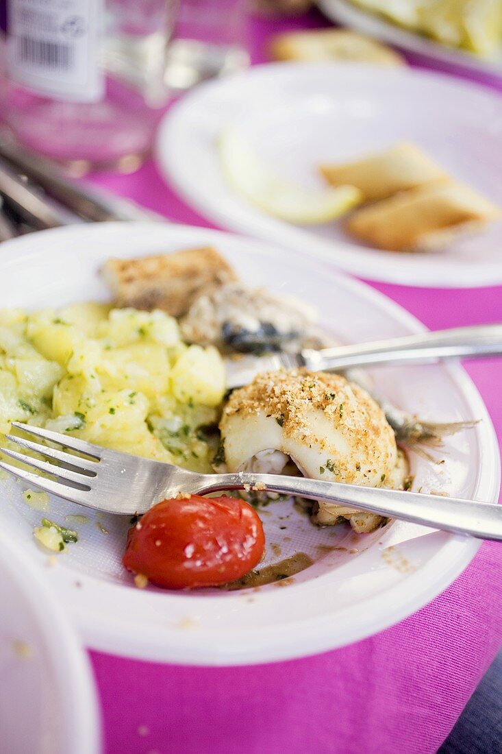 Plate with remains of fish and potato salad