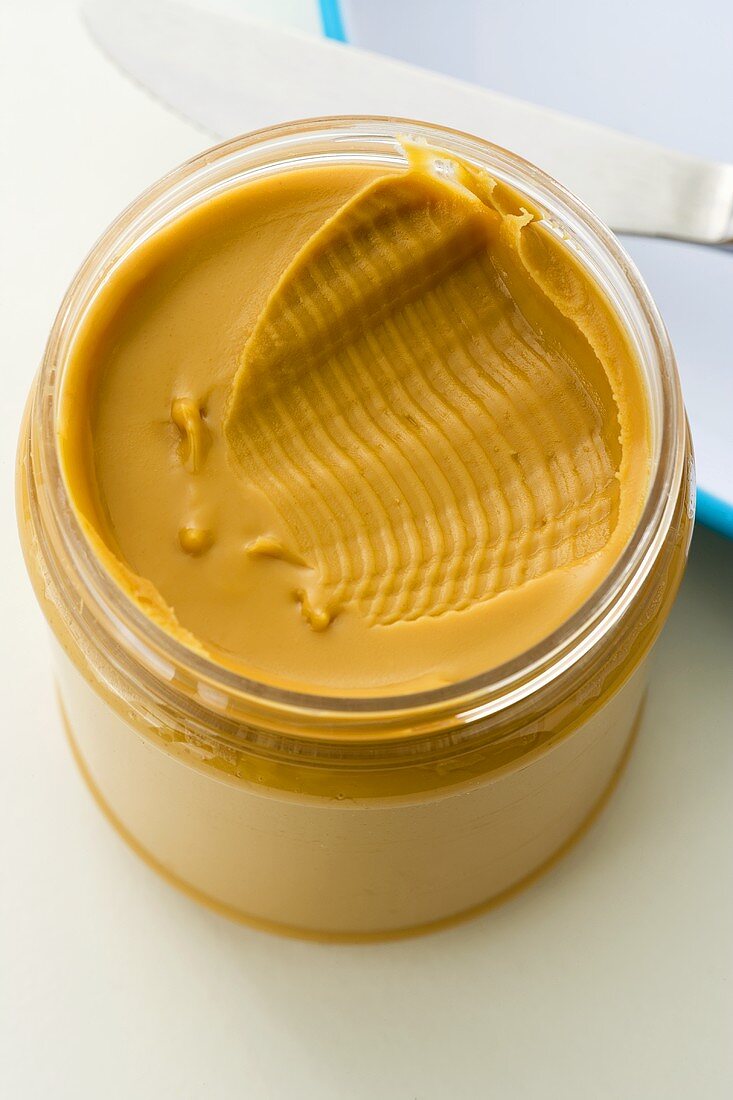 Opened Jar of Peanut Butter with Knife