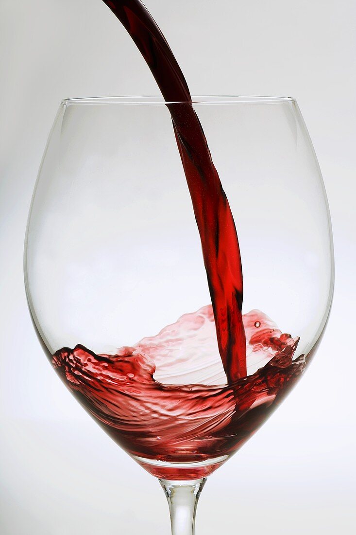 Rotwein in ein Glas gießen