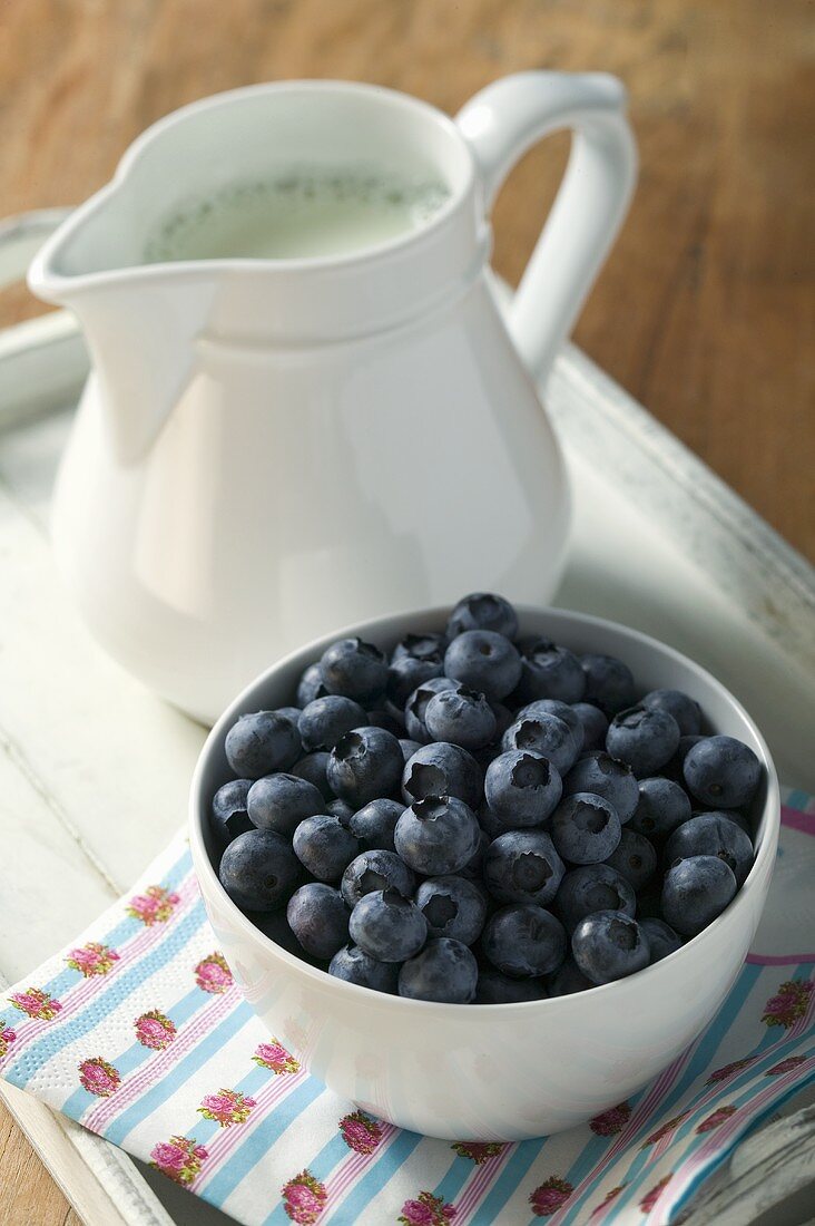 A bowl of blueberries and milk jug