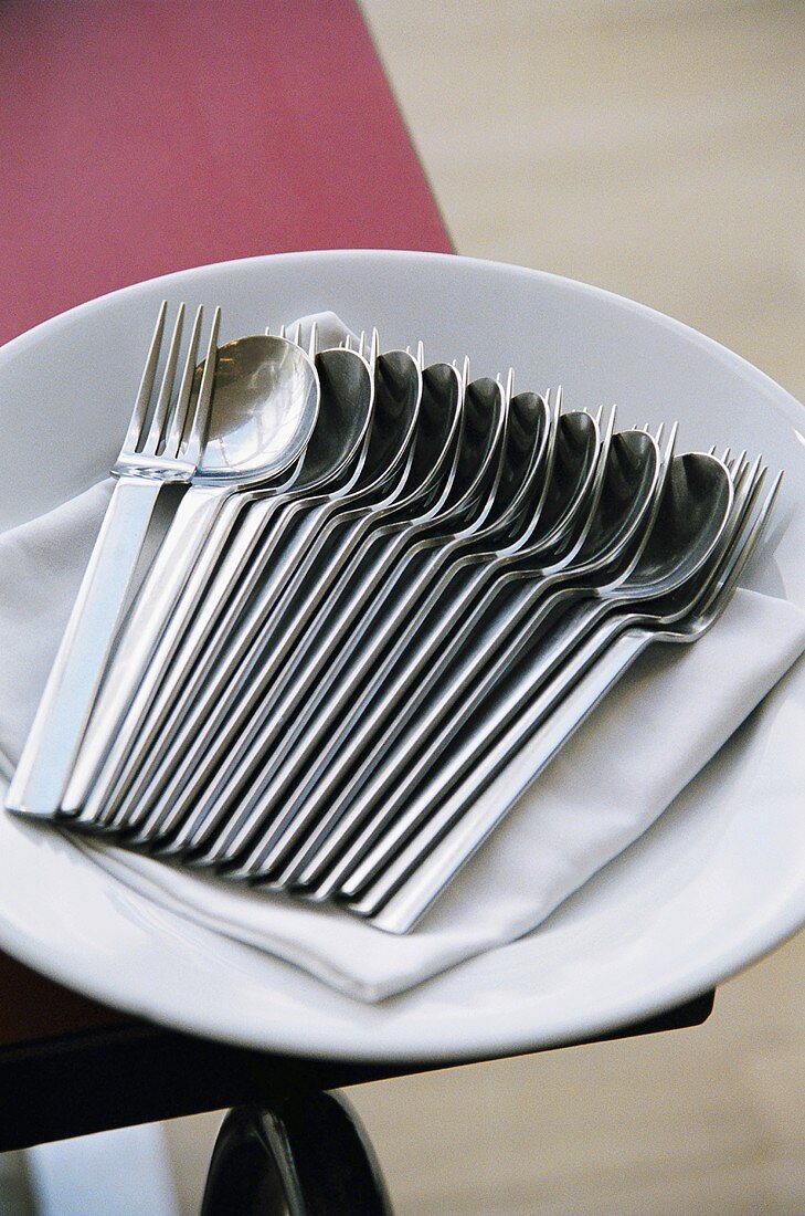 Spoons and forks with napkin on a plate