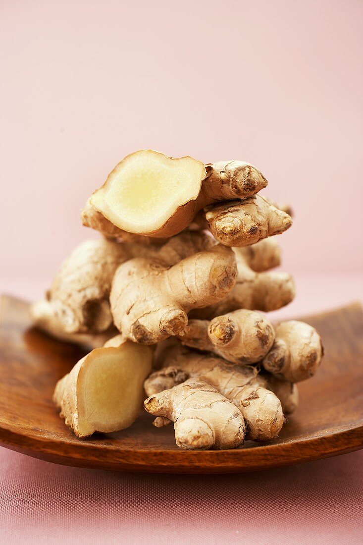 Several ginger roots in a wooden bowl