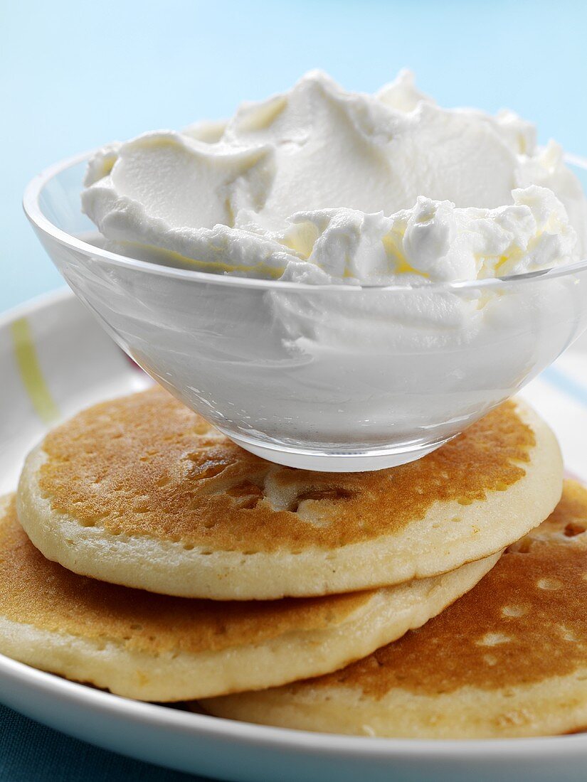 A dish of whipped cream on pancakes
