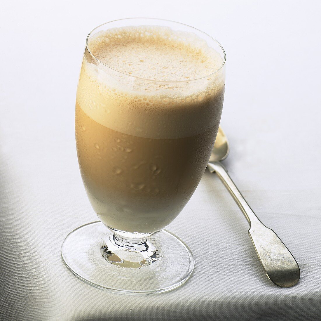 A glass of milky coffee with milk froth