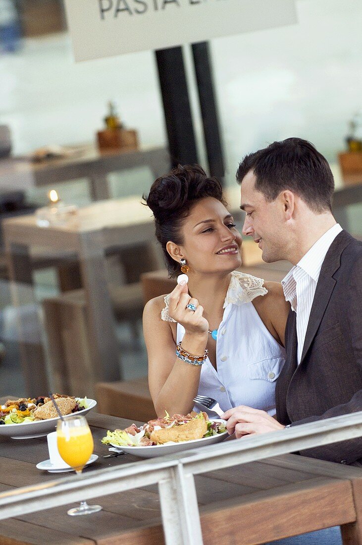 Couple sitting at outdoor restaurant table with meal