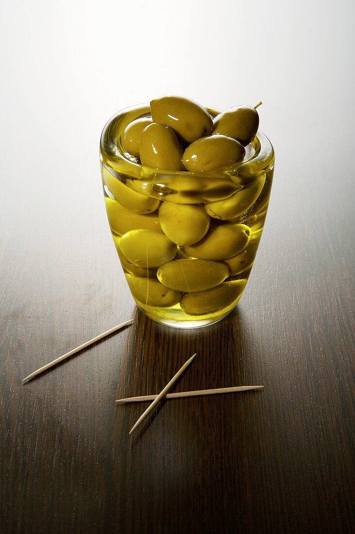 Grüne Oliven im Glas mit Olivenöl