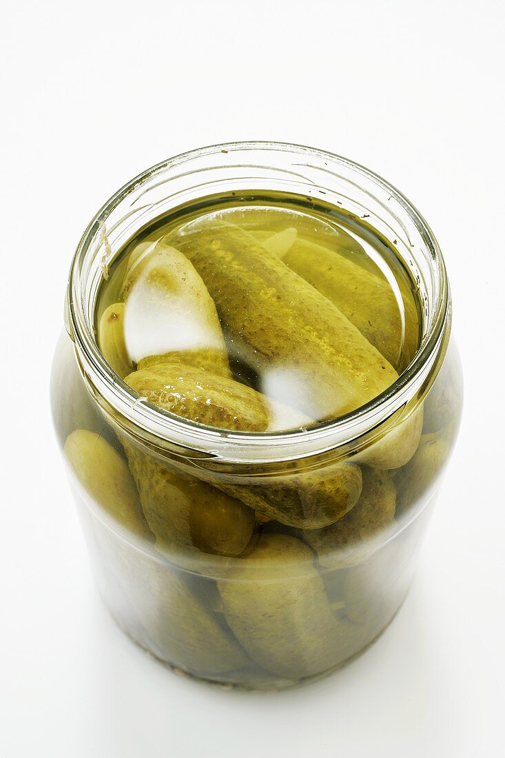 Pickled gherkins in a jar on a light background