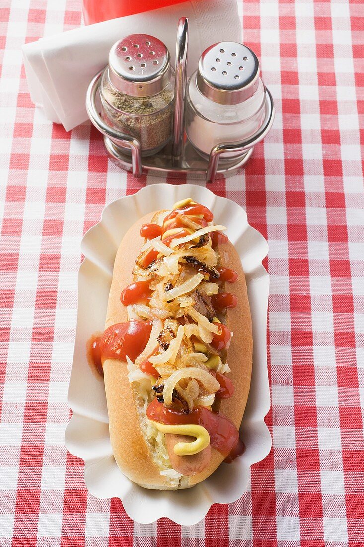 Hot dog with ketchup and onions, salt and pepper shakers