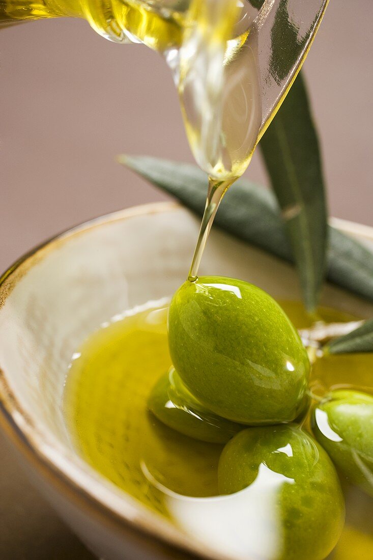Pouring olive oil over fresh green olives