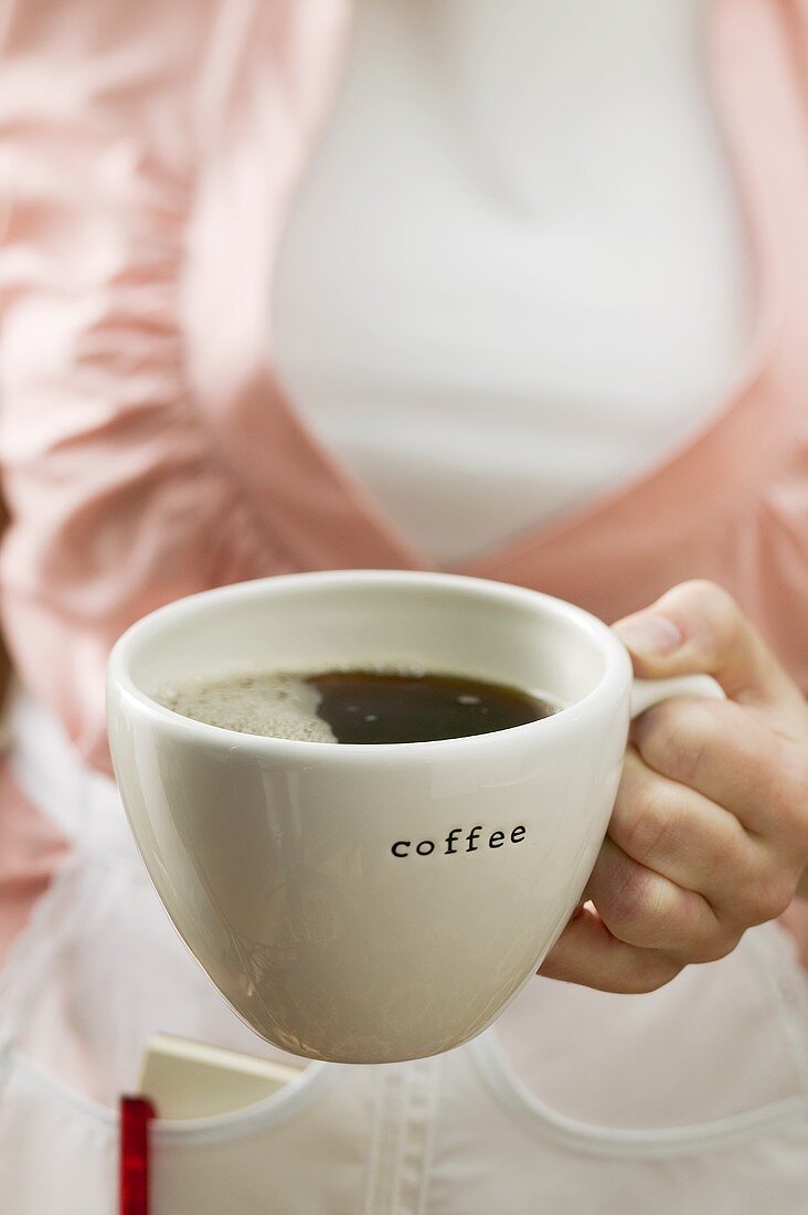 Kellnerin hält Kaffeetasse