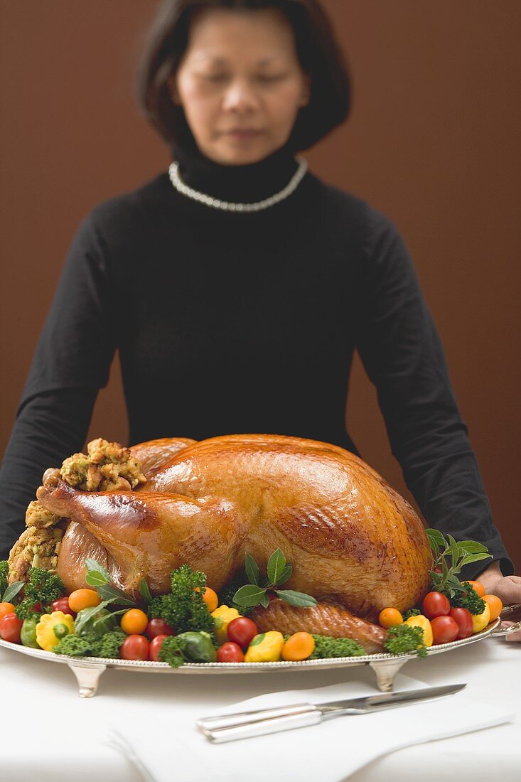 Woman holding a stuffed roast turkey on a platter