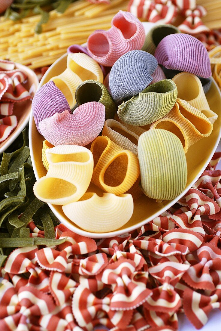 Various types of coloured pasta, some in dish