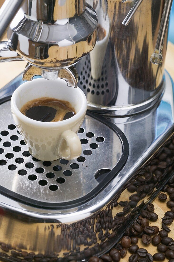 Cup of espresso on espresso machine, coffee beans
