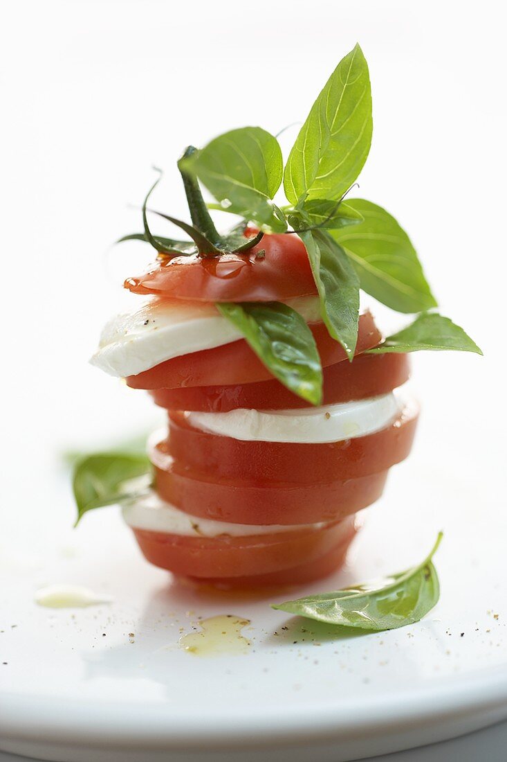 Turm aus Tomaten- und Mozzarellascheiben mit Basilikum