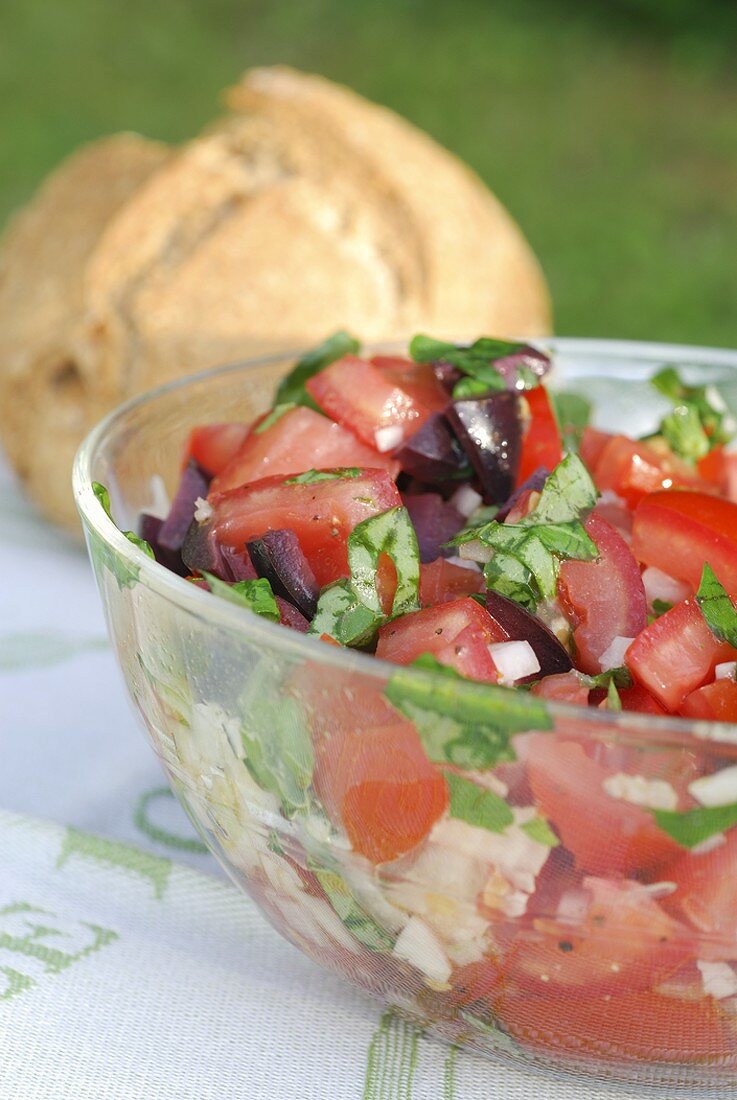 Tomato salad with olives in glass bowl