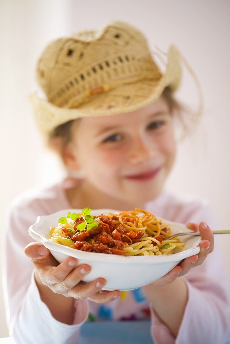 Mädchen hält Teller Spaghetti Bolognese