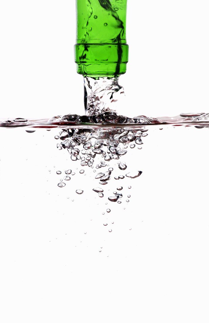 Wasser fliesst aus grüner Flasche