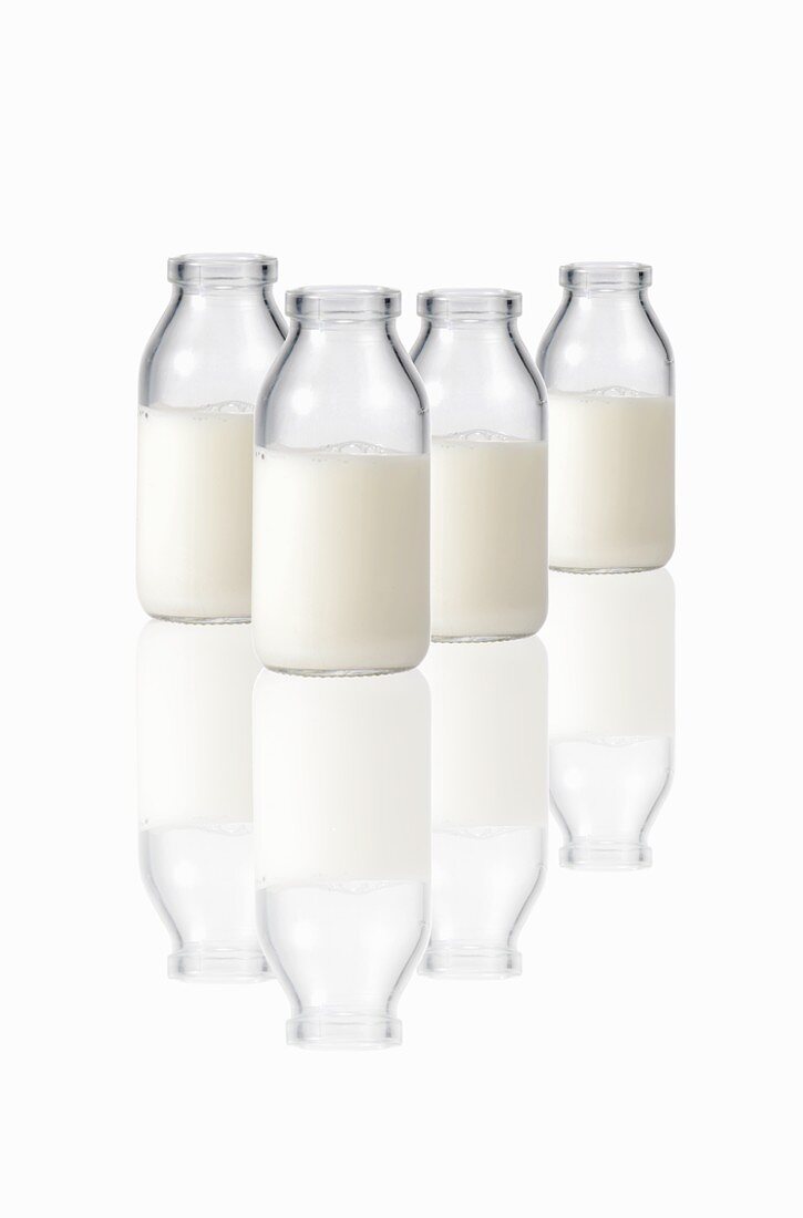 Four milk bottles on reflective surface