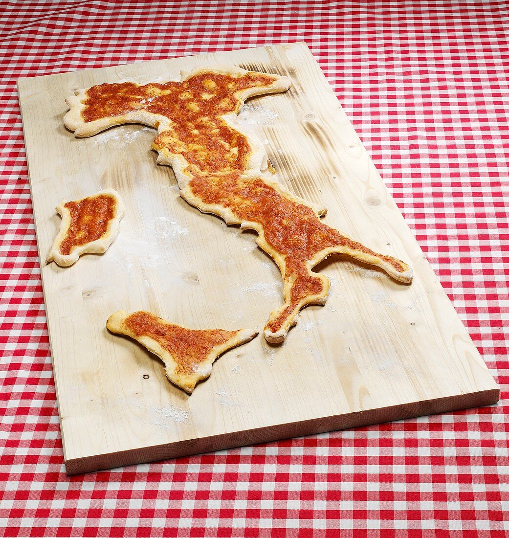 Pizza in Form der Landkarte von Italien auf Schneidebrett