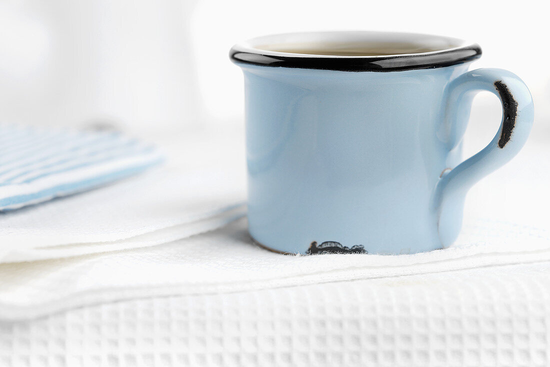 Kaffee in blauer Tasse auf weißem Geschirrtuch