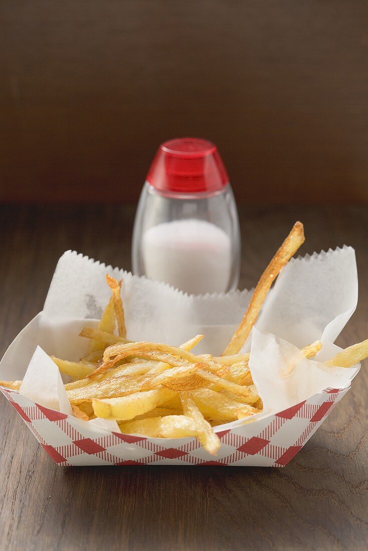 Chips in cardboard container, salt shaker behind