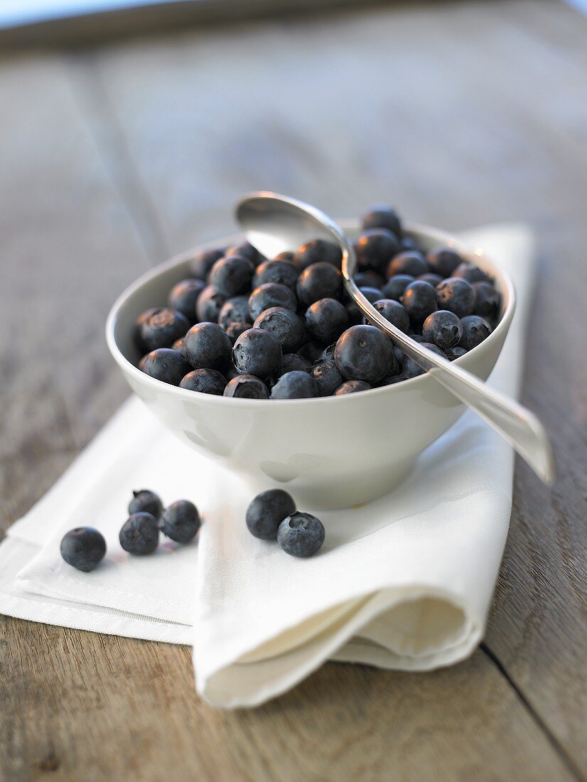 Fresh blueberries in a small bowl with spoon