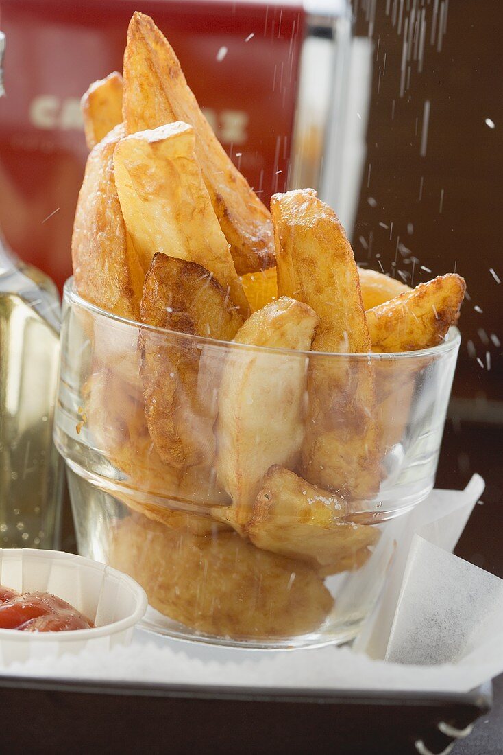 Sprinkling salt over potato wedges in a glass