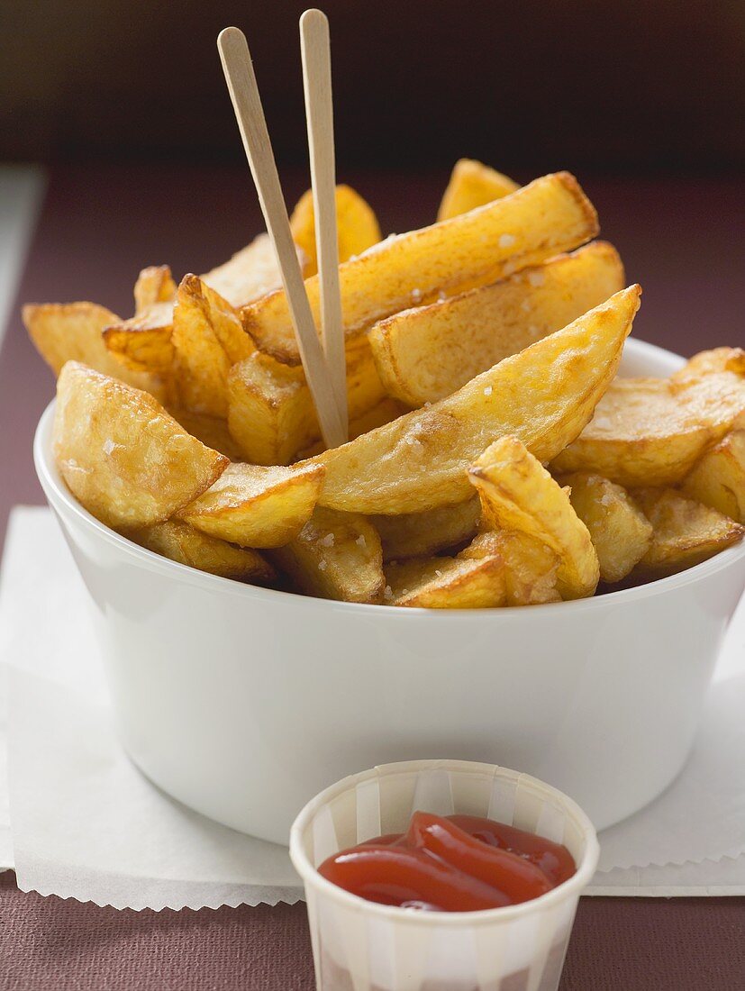 Potato wedges with wooden sticks and ketchup