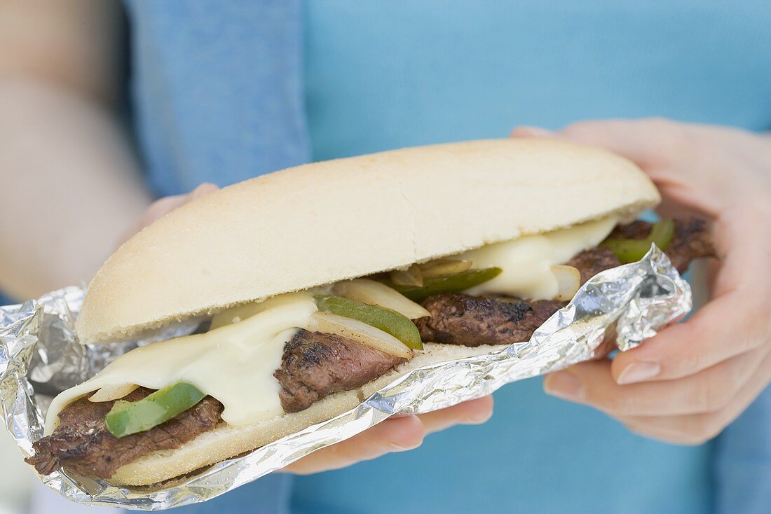 Woman holding grilled meat and cheese sandwich