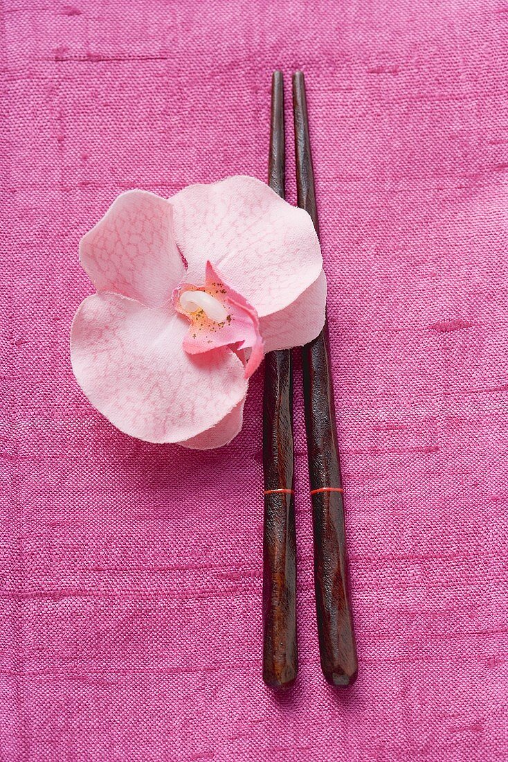 Chopsticks and orchid on pink fabric