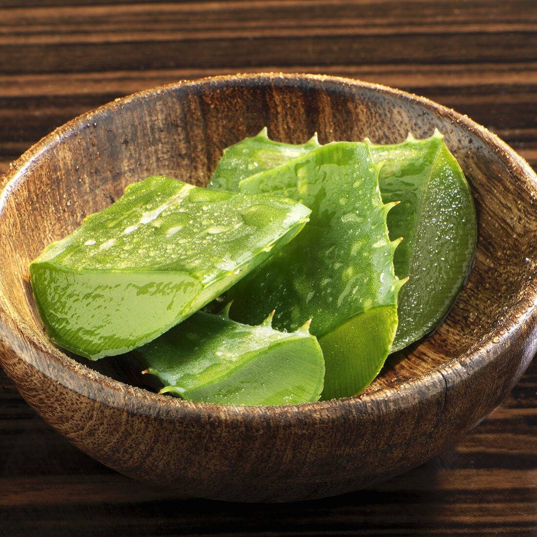 Pieces of Aloe vera leaves in wooden bowl