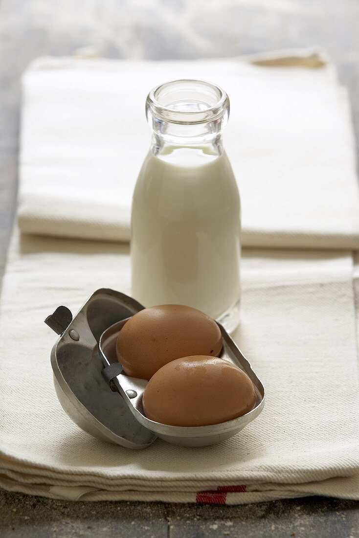 Two eggs and bottle of milk on tea towel