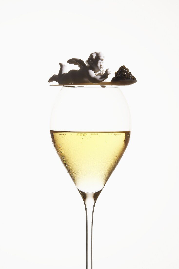 Spoonful of caviar with angel on glass of champagne