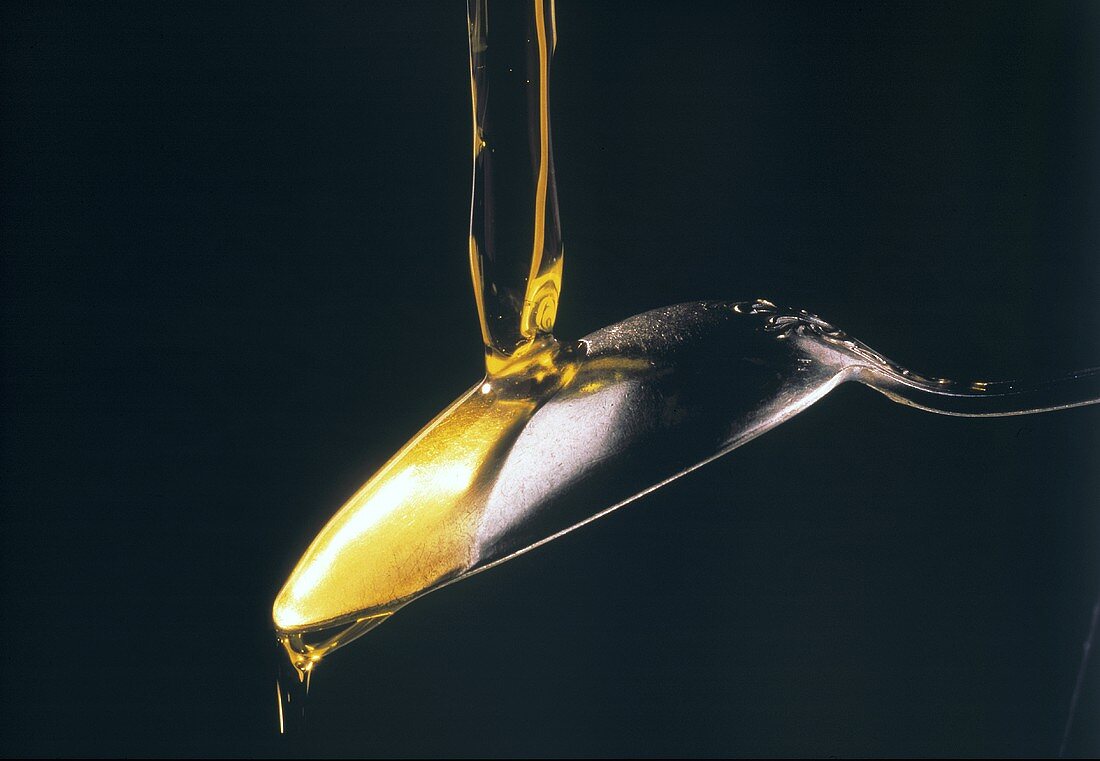 Olive Oil Being Poured Over Back of Spoon
