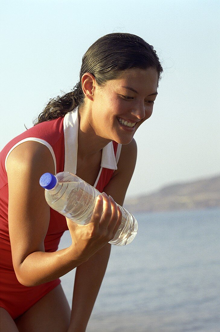 Junge Frau trainiert mit einer Wasserflasche in der Hand