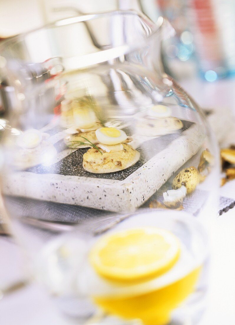 Mushroom canapés with quail's eggs, carafe of lemonade in front