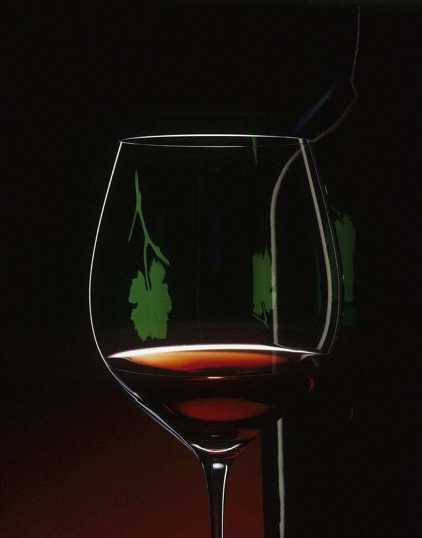A glass of red wine with a projected image of a vine leaf