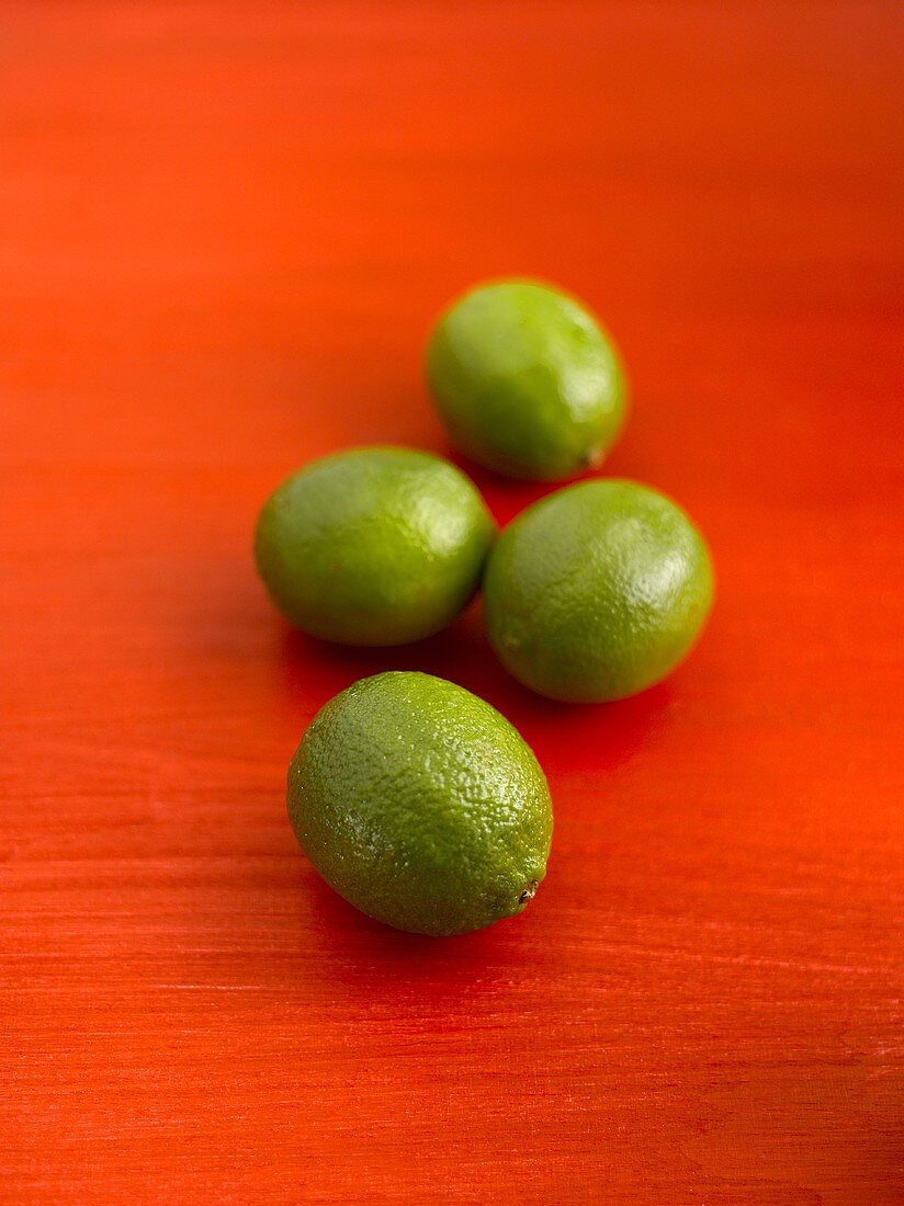 Four limes on red background