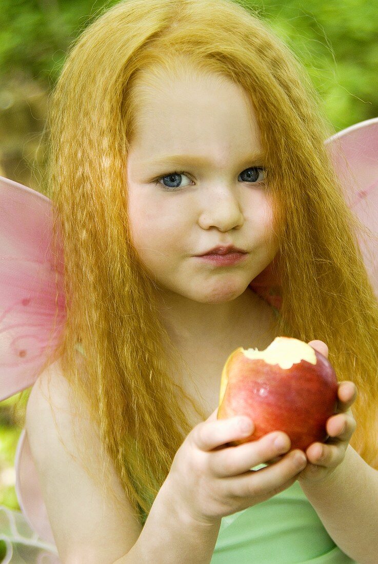 Young girl dressed as fairy with an apple