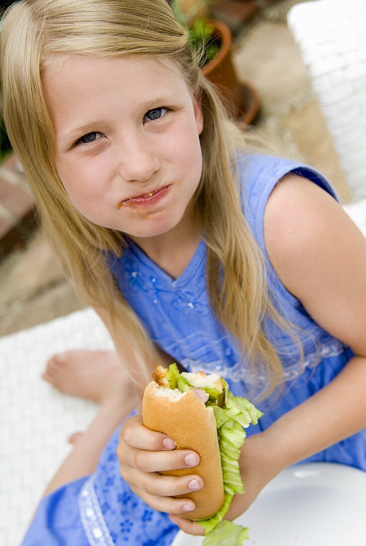 Blondes Mädchen isst Hot Dog