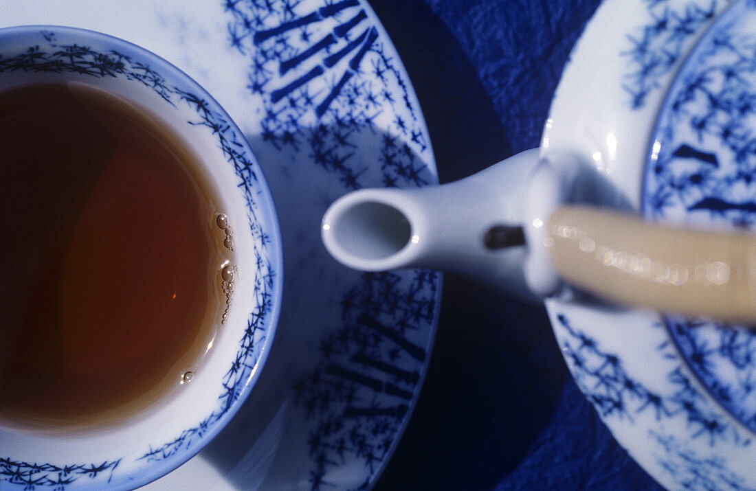 Teekanne und Teetasse mit Tee gefüllt
