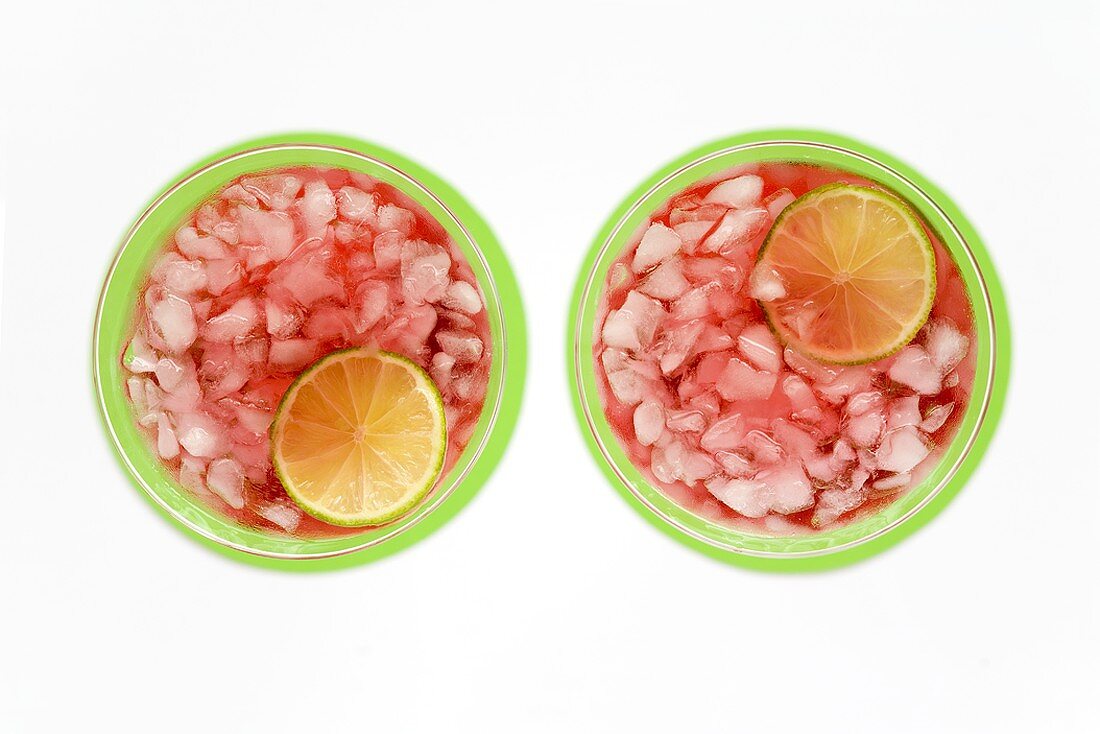 Two cranberry drinks with crushed ice and slices of lime