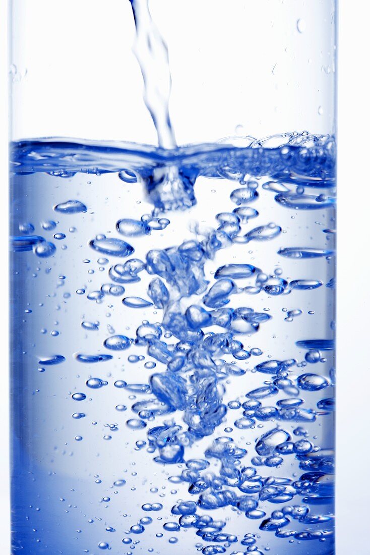 Mineralwasser ins Glas gießen