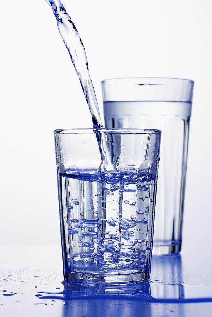 Wasser wird in ein Wasserglas gegossen